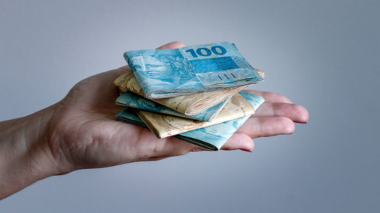 Hands holding Brazilian real notes, money from Brazil, notes of Real, Brazil BRL banknote, Brazilian currency, economy and business.