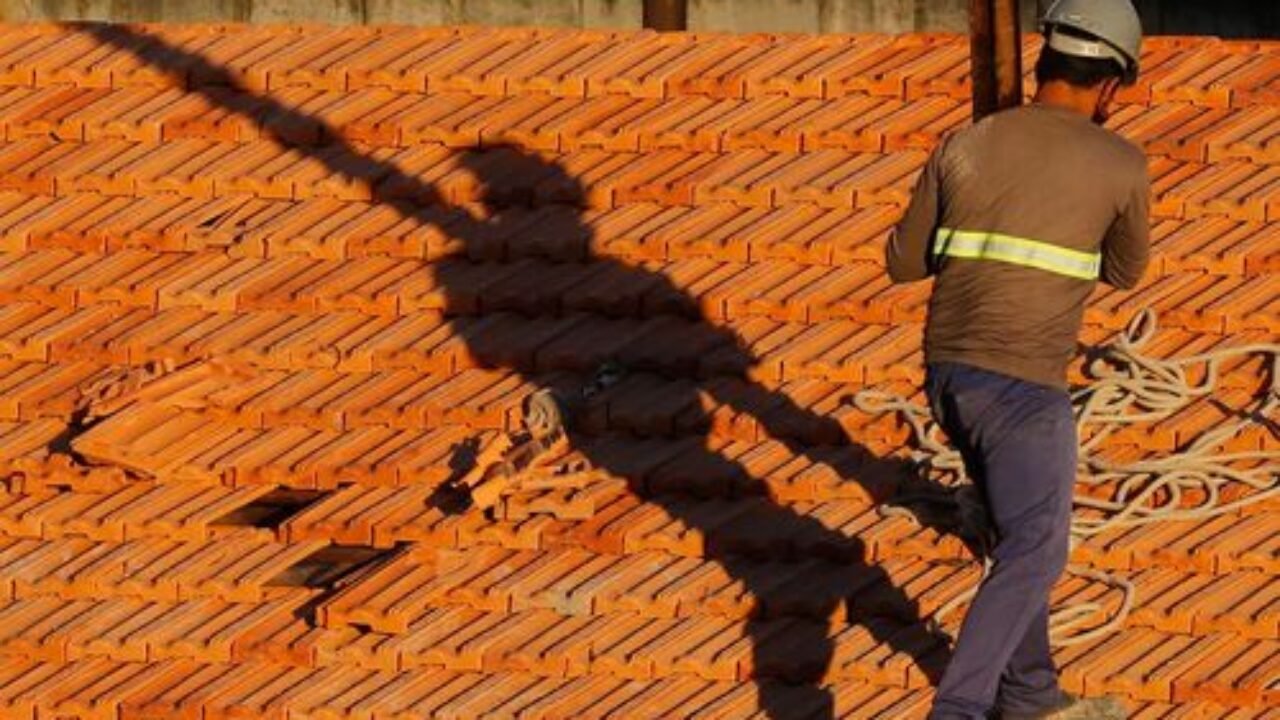 Trabalhadores da construção civil, operários reformam telhado de imóvel em obras no Centro do Rio.