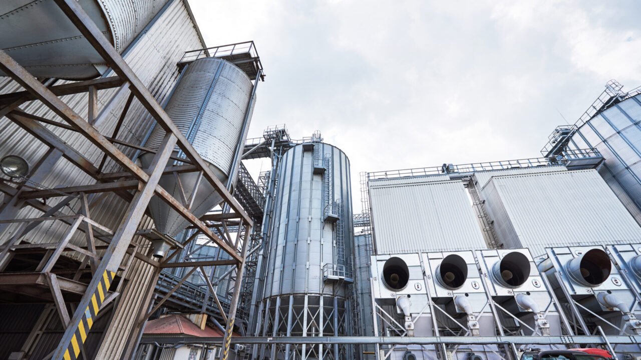 Agricultural Silos. Building Exterior. Storage and drying of grains, wheat, corn, soy, sunflower against the blue sky with white clouds.